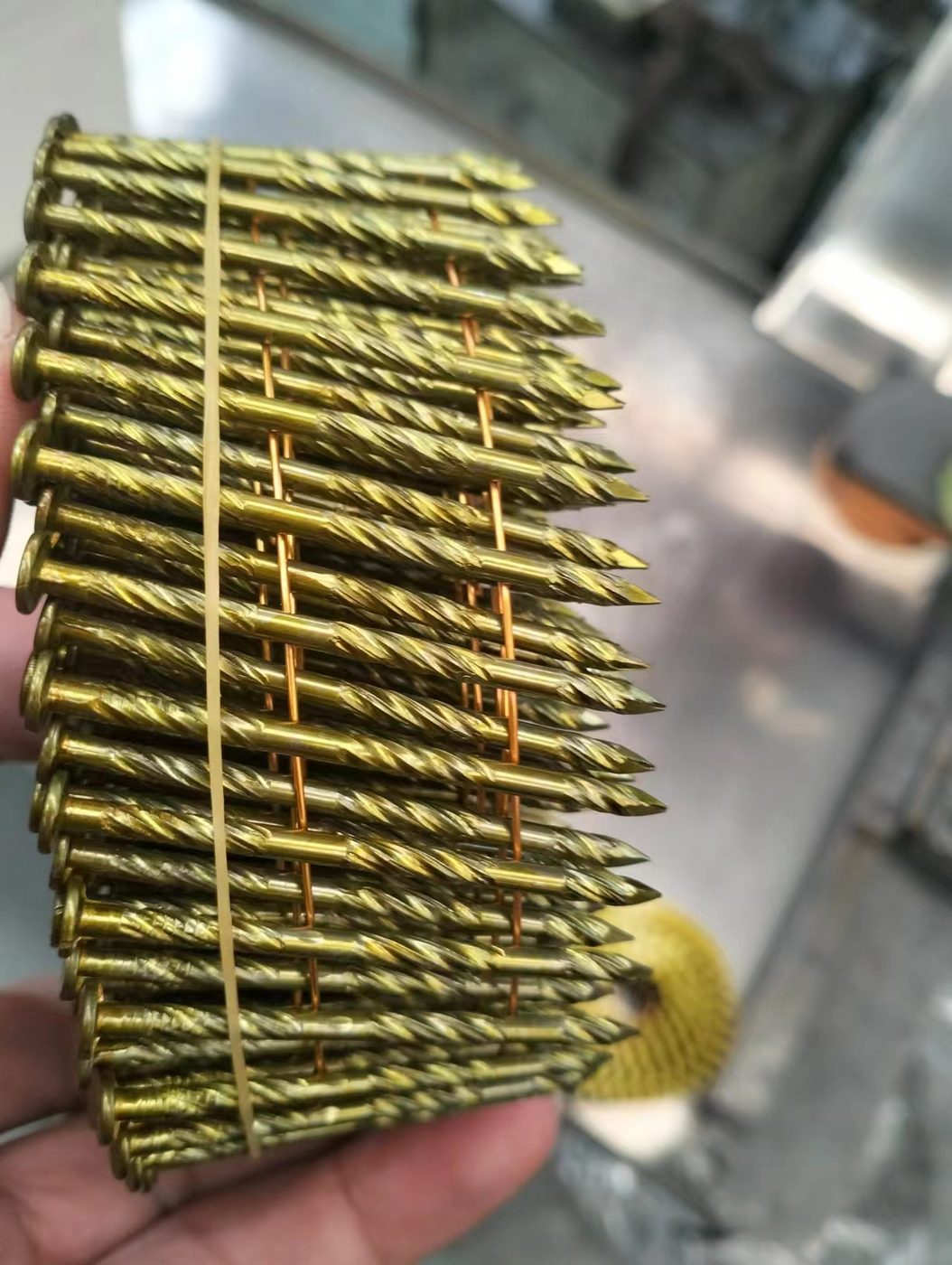 Screw-shank 2-inch coil nails held in hand